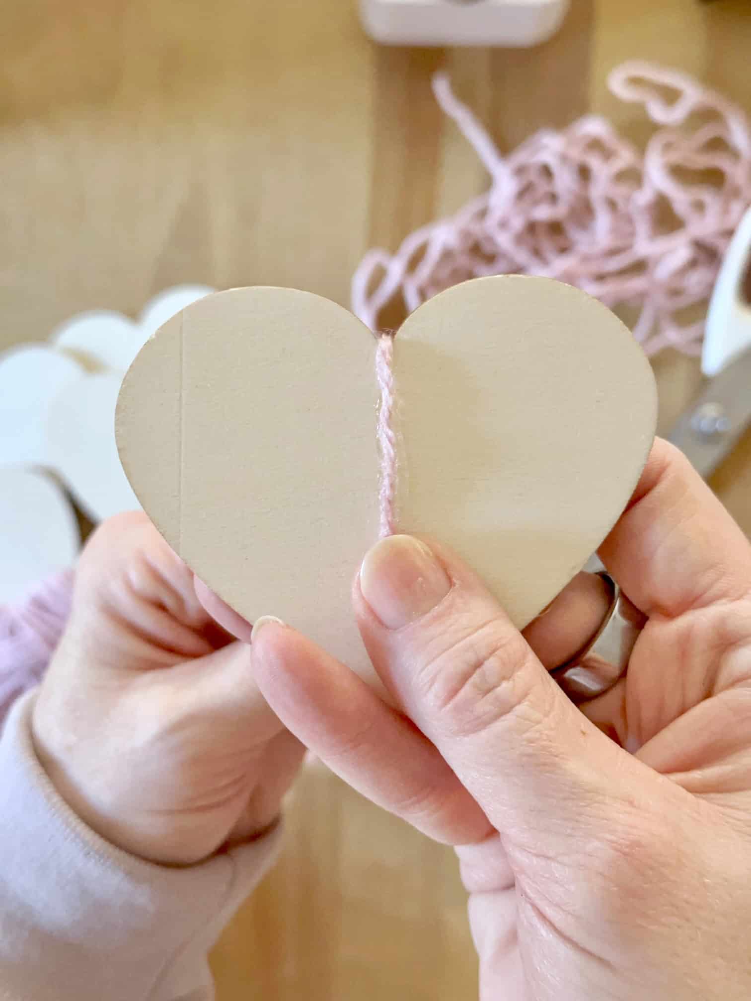 Placing a line of glue and pressing the yard to the heart to begin the wrap.