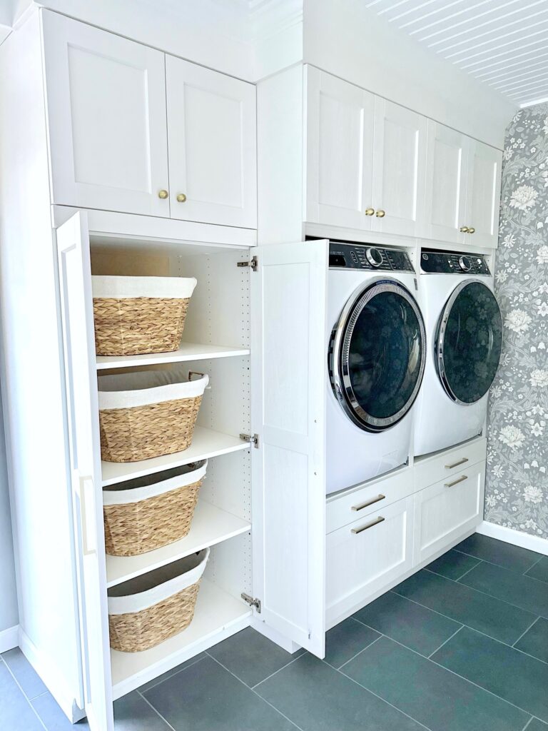 IKEA floor to ceiling white cabinets with washer and dryer plus a third tall cabinet with wicker laundry baskets. 