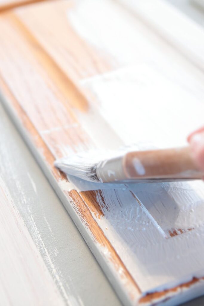 A brush painting primer on an oak cabinet door.