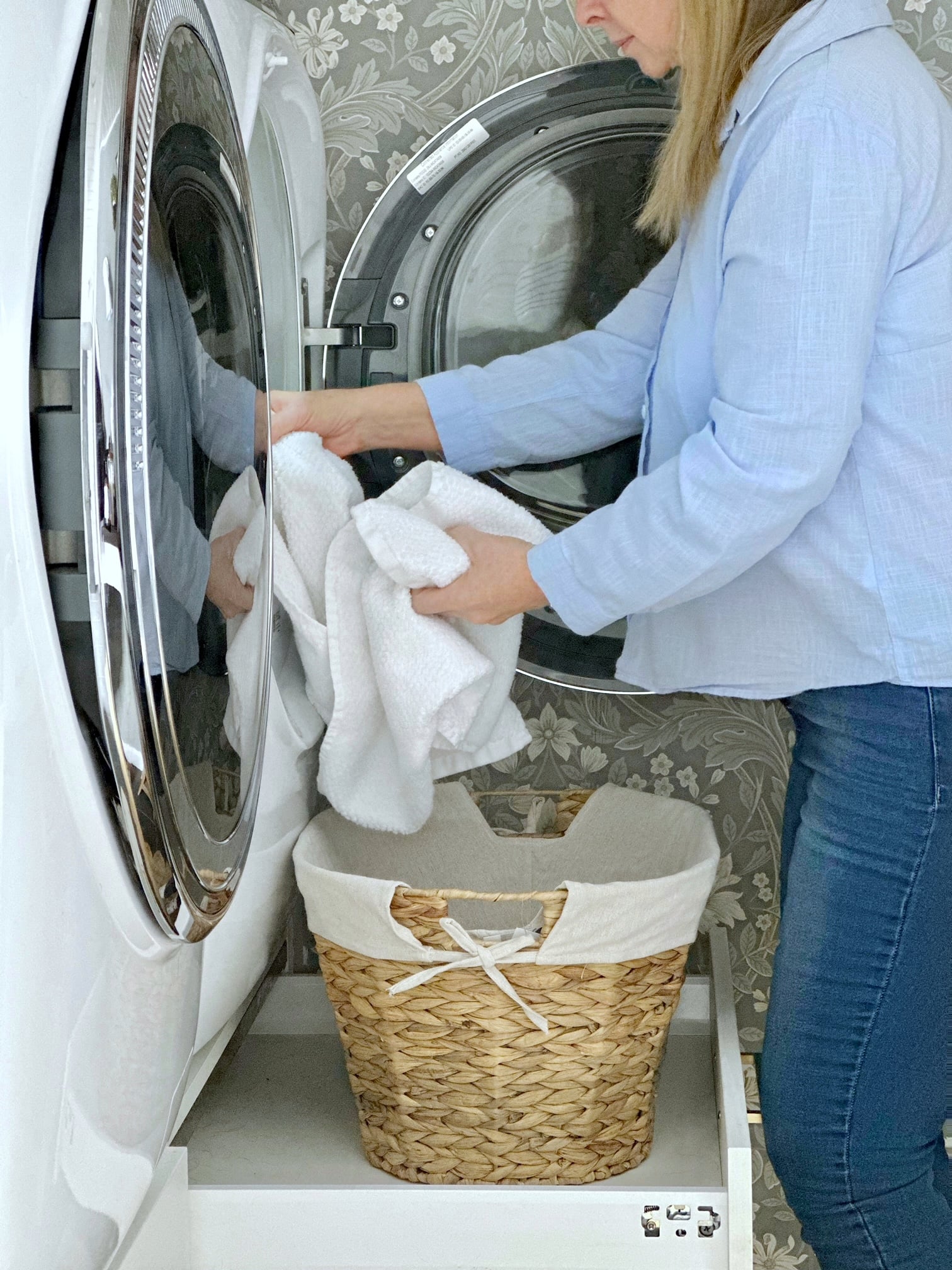 Me emptying laundry into a basket that is sitting on a pull out drawer.