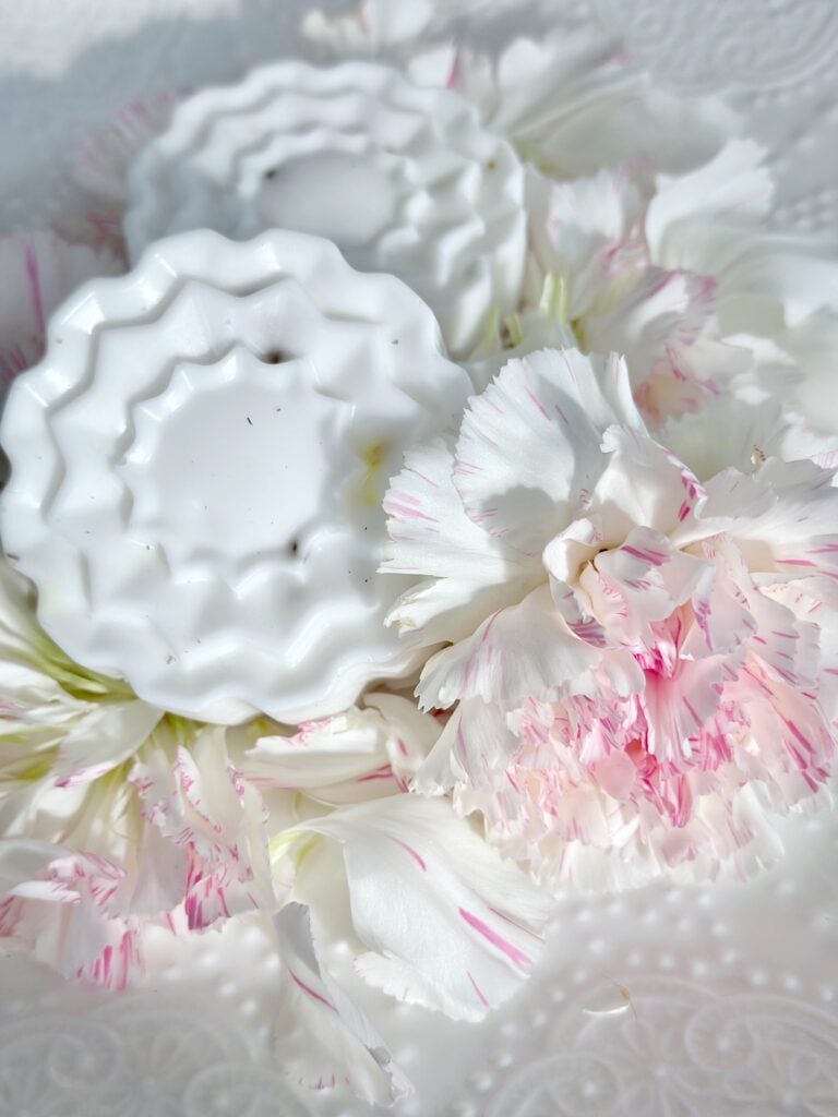 the soaps that were in a flower shape mold on a white plate with a fresh carnation next to it.