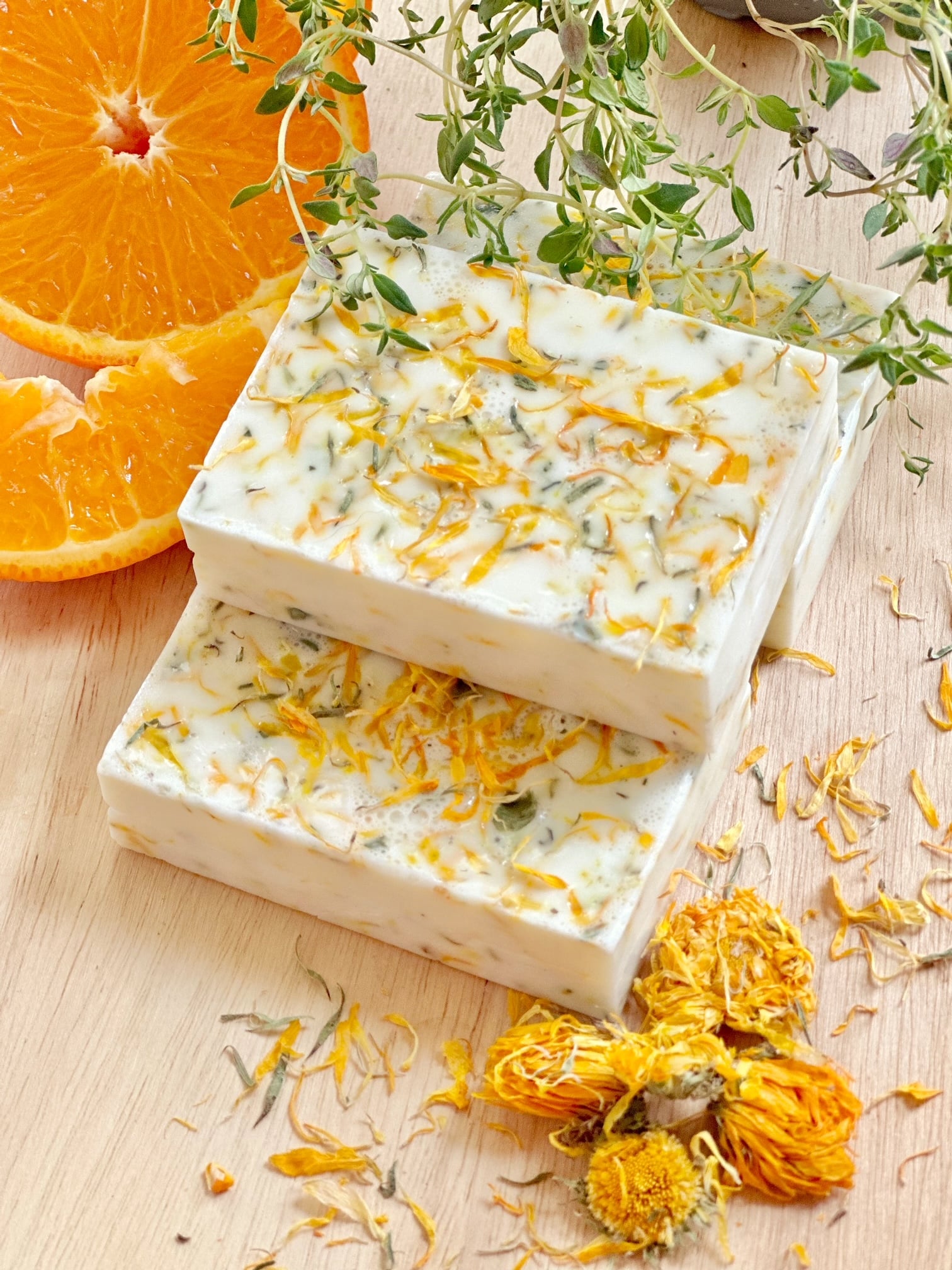 A side view of 3 soap bars stacked with the ingredients around them. 