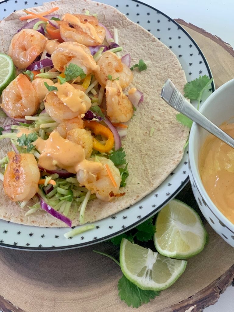 A shrimp taco on a plate with chopped cilantro. 