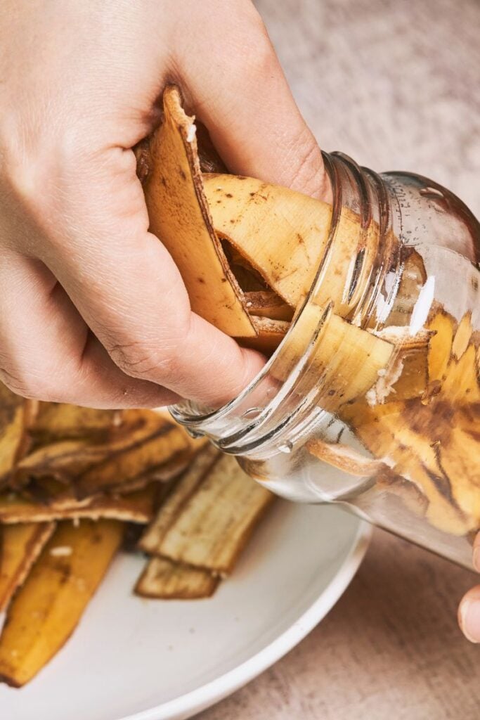 hand place banana peels in a jar. 