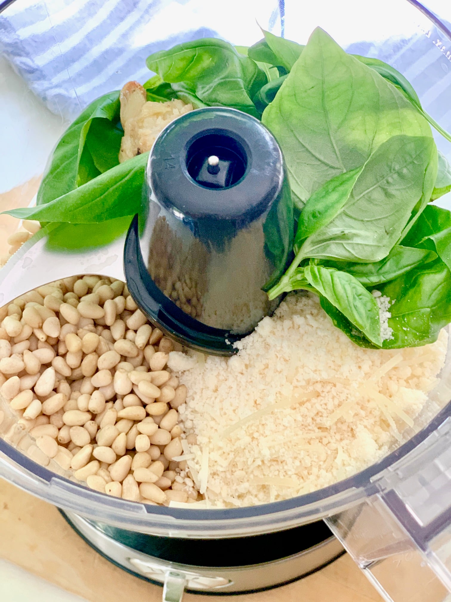 Food processor with the ingredients for basil pesto.