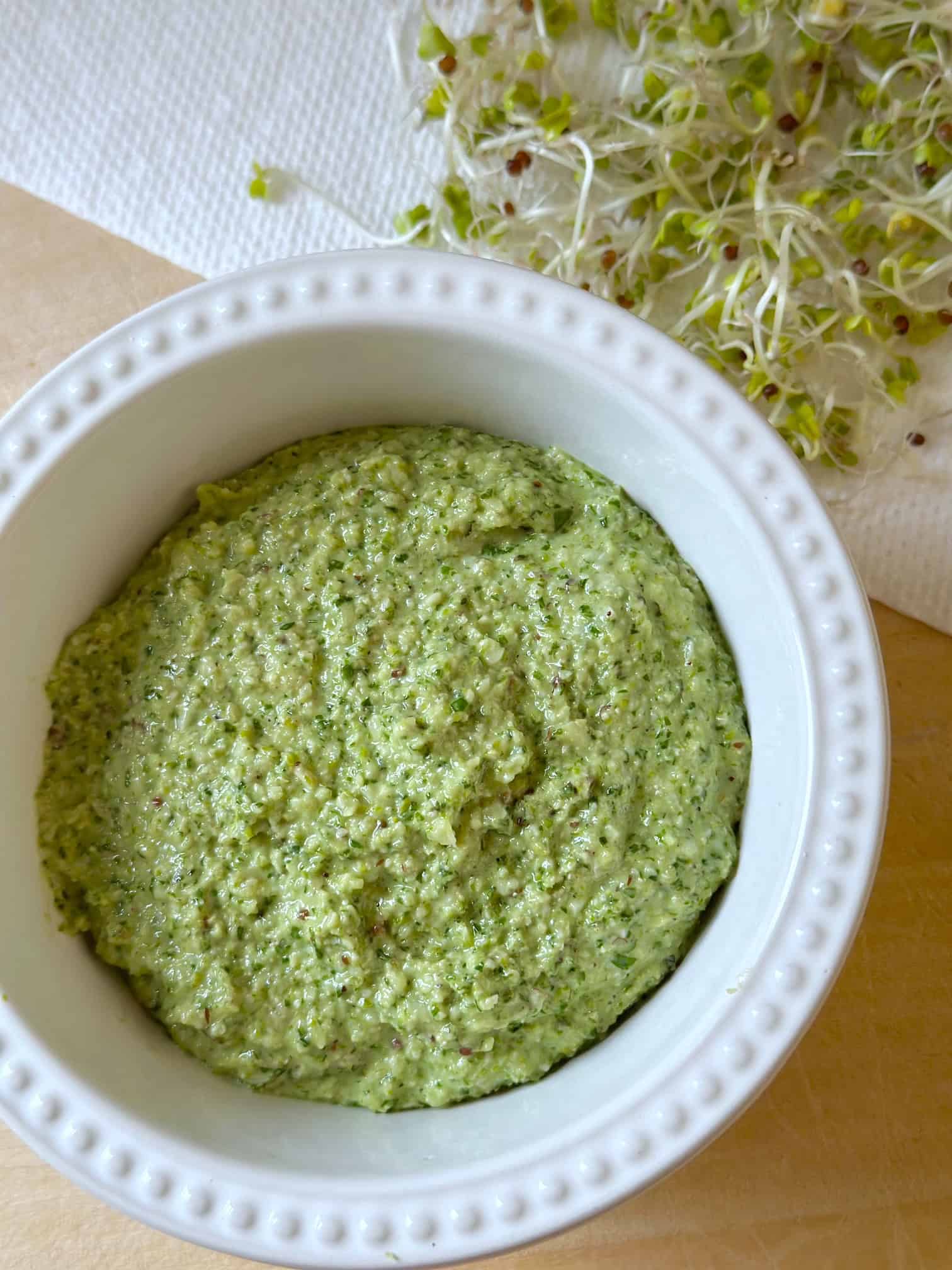 A small bowl of Lemony basil pesto with broccoli sprouts. 