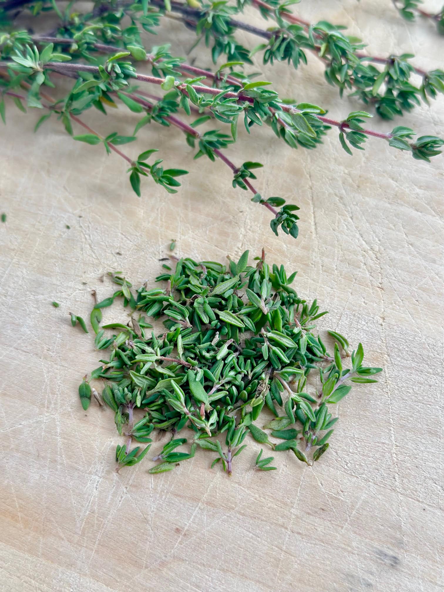 Fresh thyme leaves on a cutting board. 