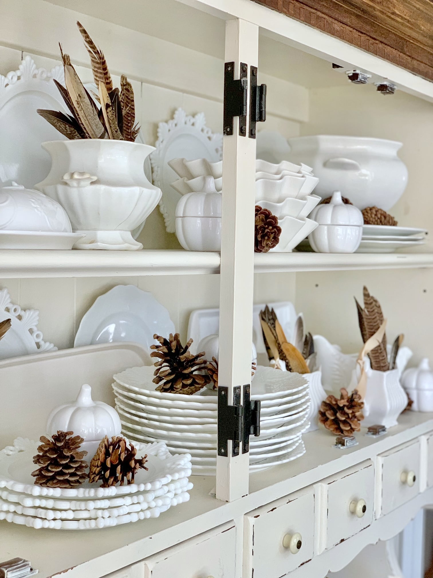 An open hutch with white dish ware and fall elements creating a natural fall decor display.