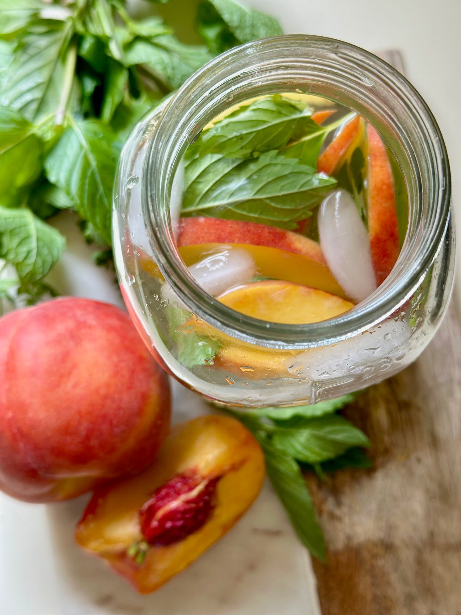 atop down view of peach and mint in a glass jar of water.