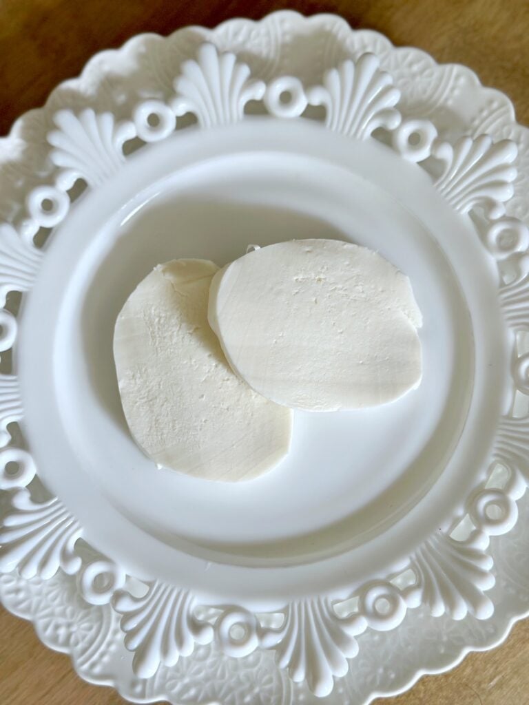 2 rounds of sliced mozzarella cheese on a plate. 
