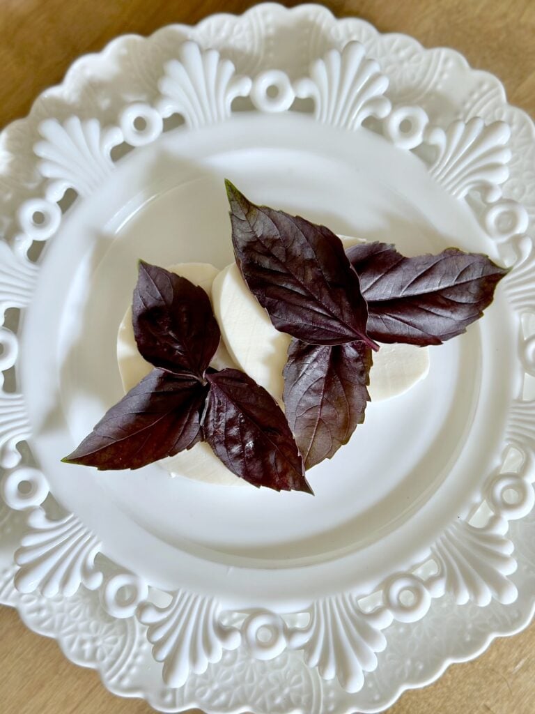 purple basil leaves layered on top of the cheese.