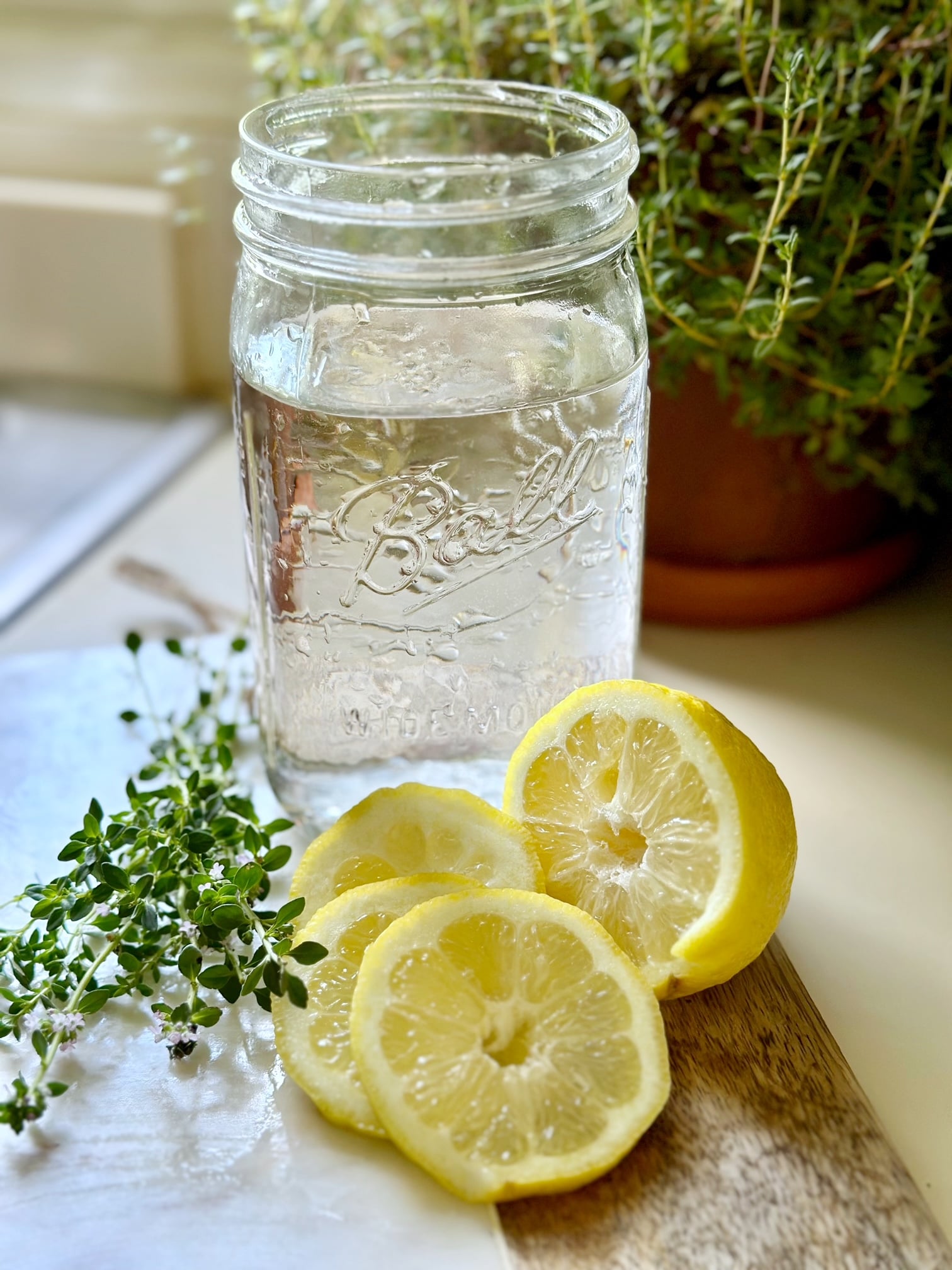 a jar of water, sliced lemons and a little bundle of fresh thyme.