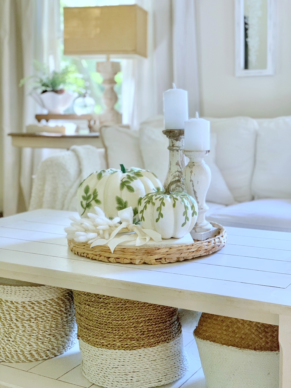 White coffee table with white sofa. the DIY Leaf Vine pumpkins are situated in a coffee table vignette consisting of a tray, white books, bunny tail cluster and chippy candle sticks. 