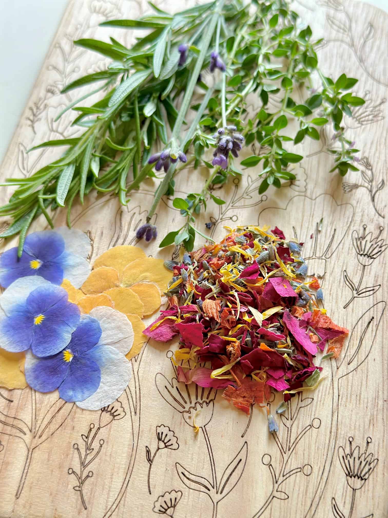 Herbs, pile of chopped edible flowers and pansies on a cutting board.