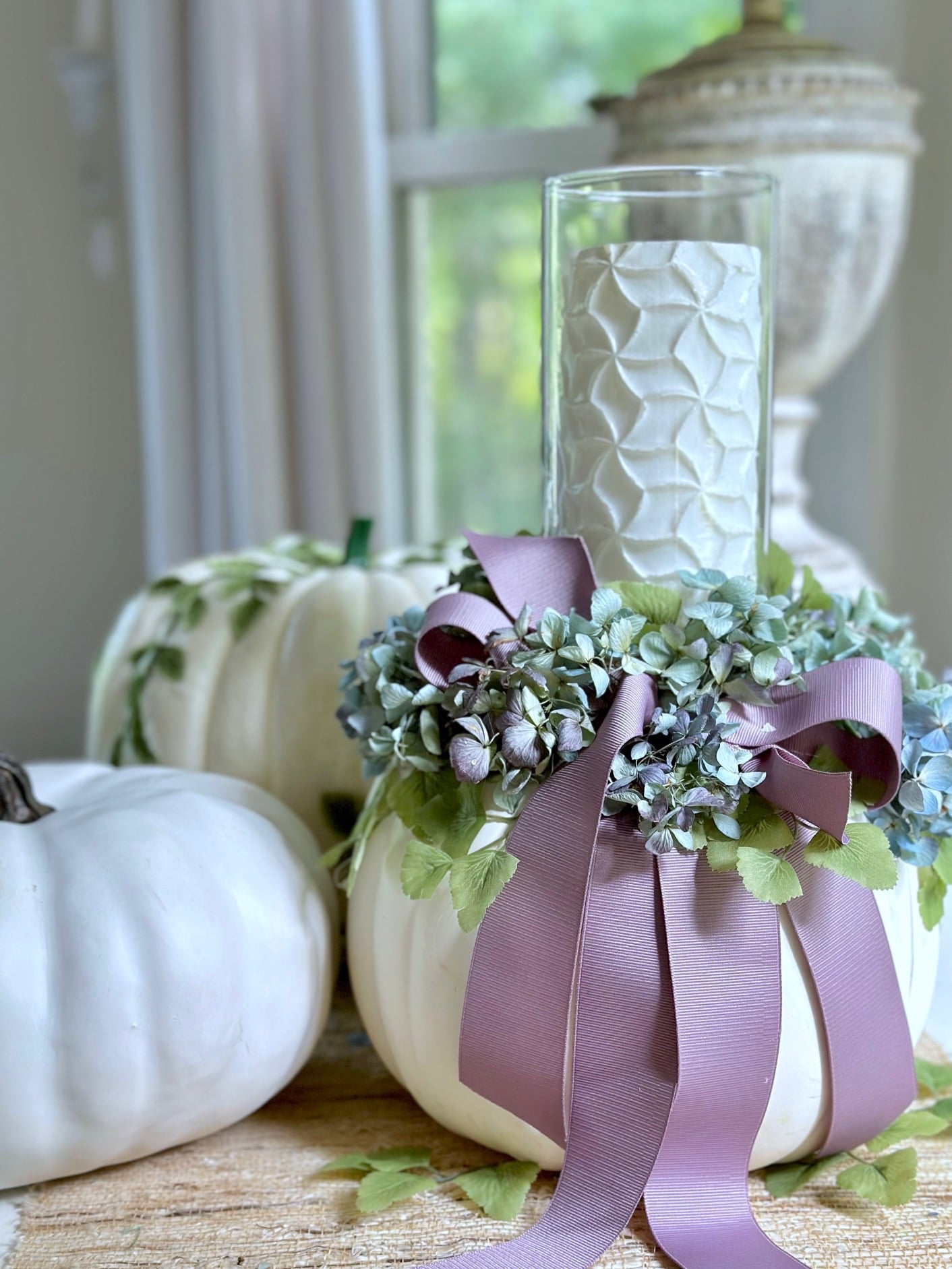 White pumpkin with dried blue hydrangea and a cylinder with candle.