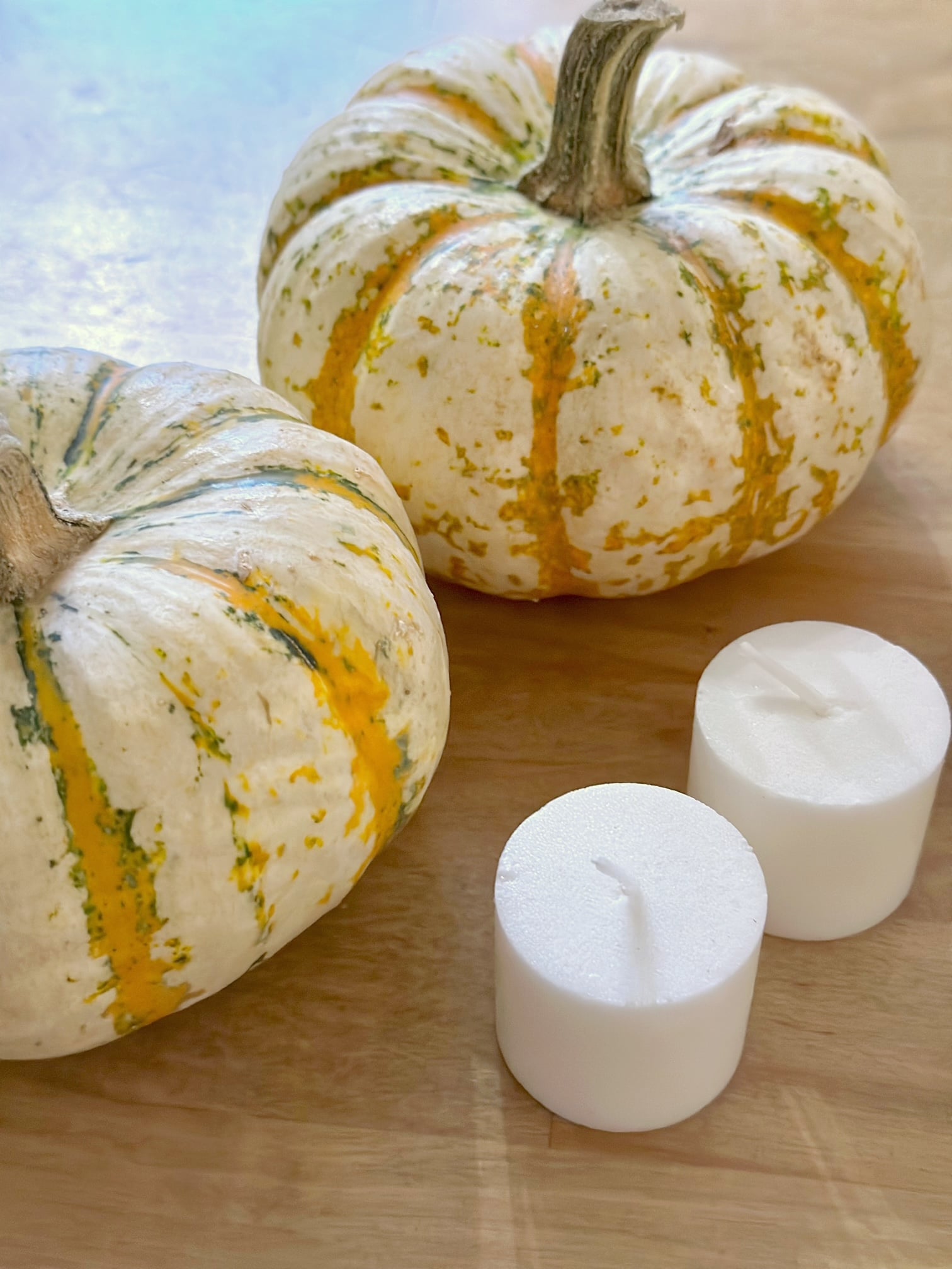 2 mini heirloom pumpkins with 2 white votive candles.