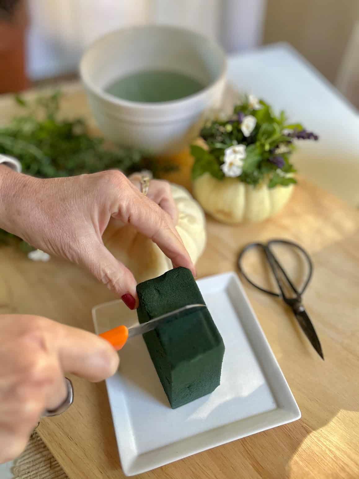 Cutting floral foam to fit in the pumpkin.