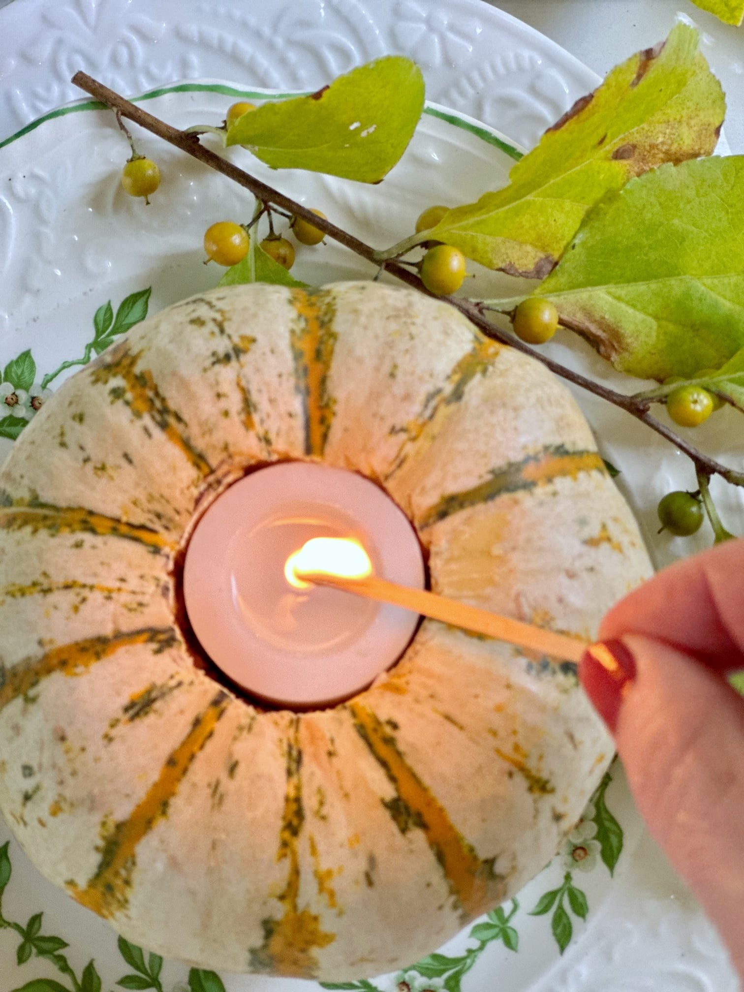 Me lighting the votive candle that is in the pumpkin with a match.