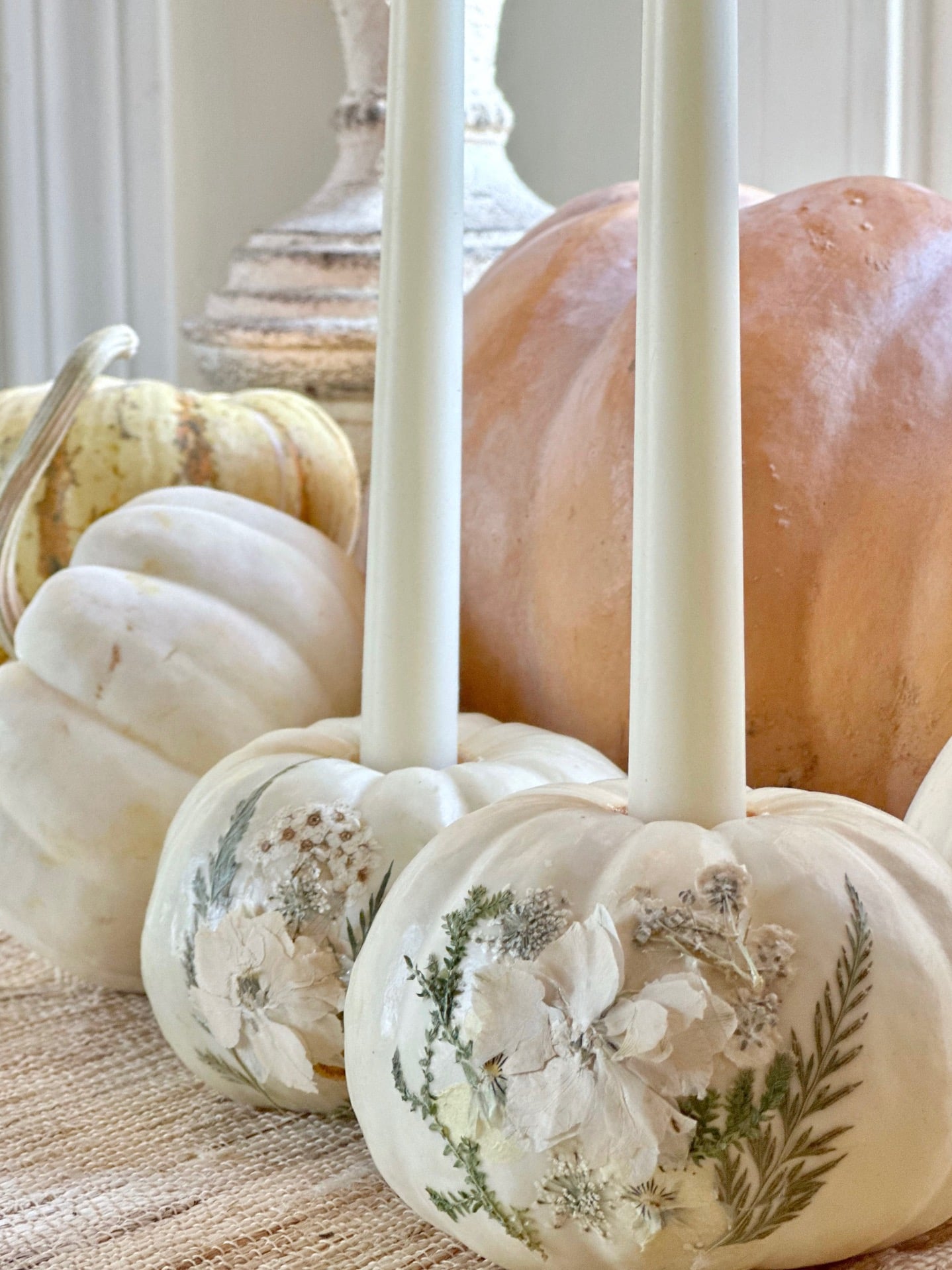 The completed white mini pumpkins with pressed flowers with a candle.