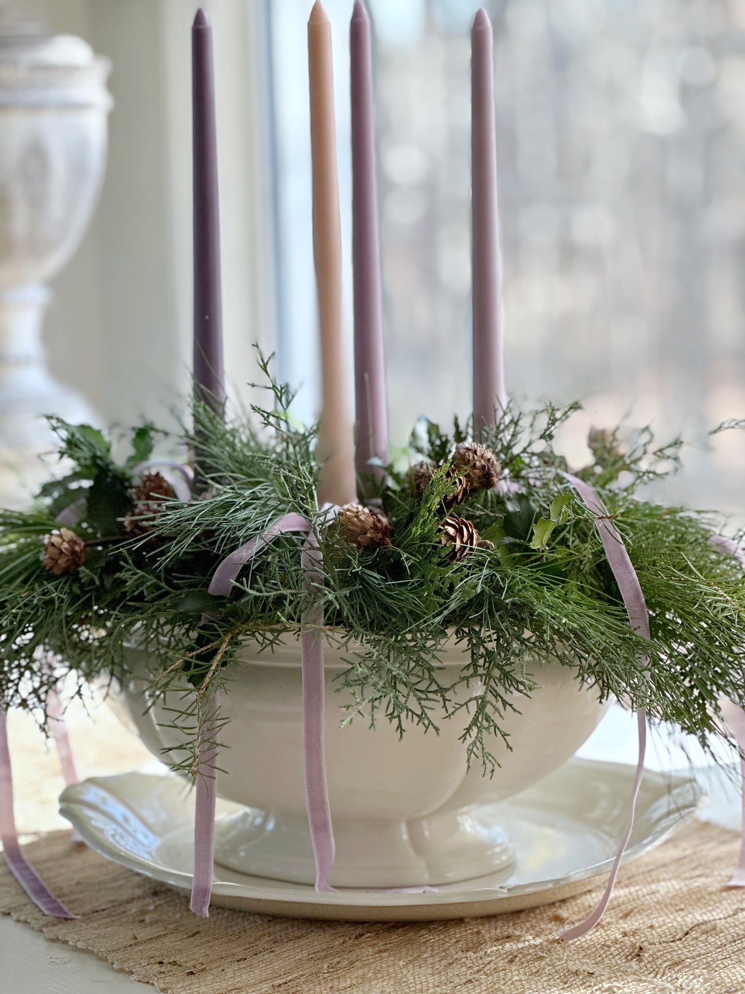 A holiday centerpiece with advent candles and ribbons.