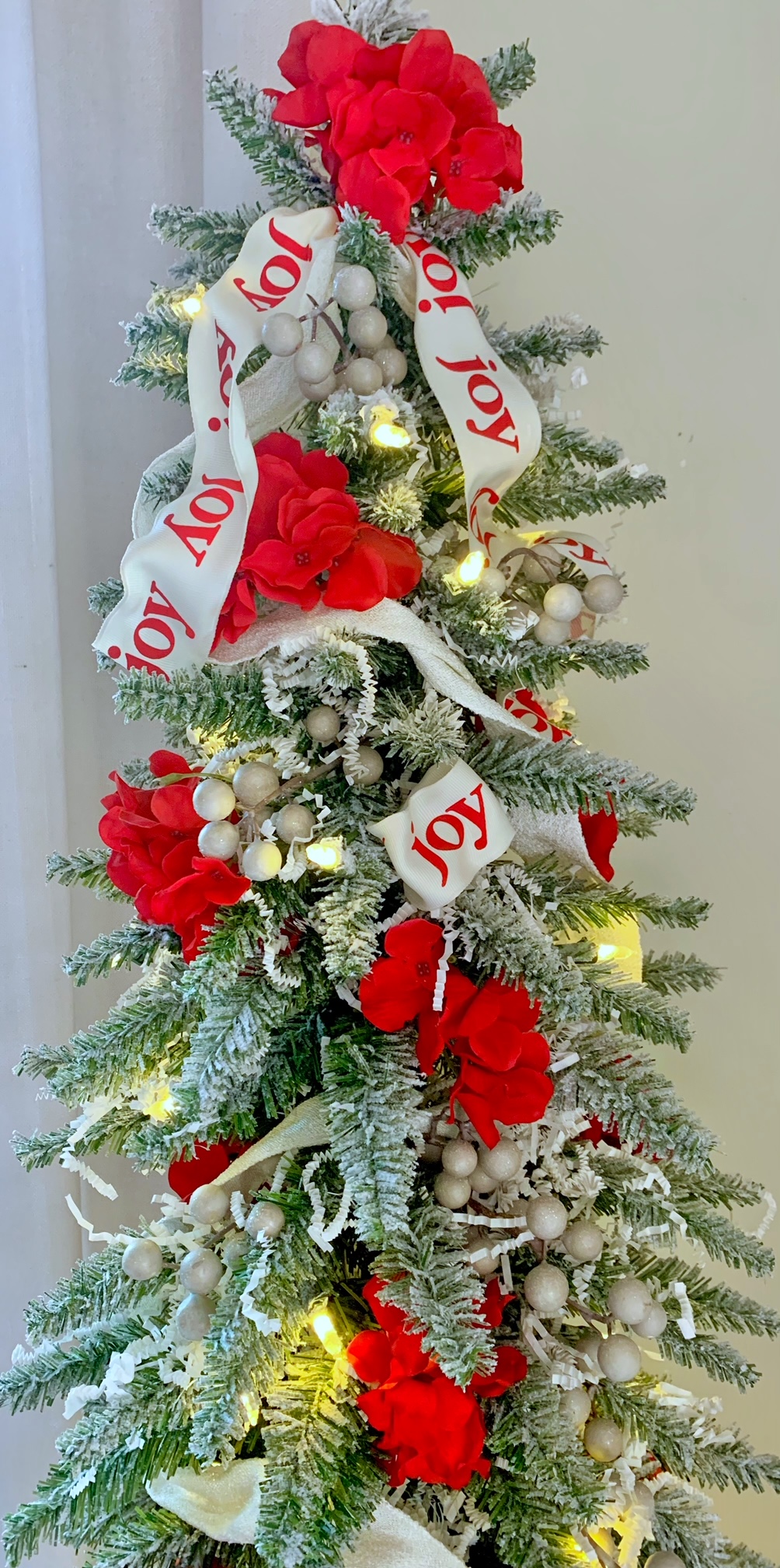 A pencil tree decorated red and white with ribbon that reads "Joy".