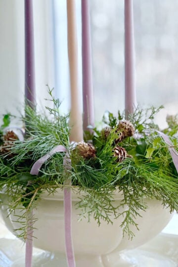 A vintage inspired advent wreath centerpiece featuring soft advent candles and fresh greens.
