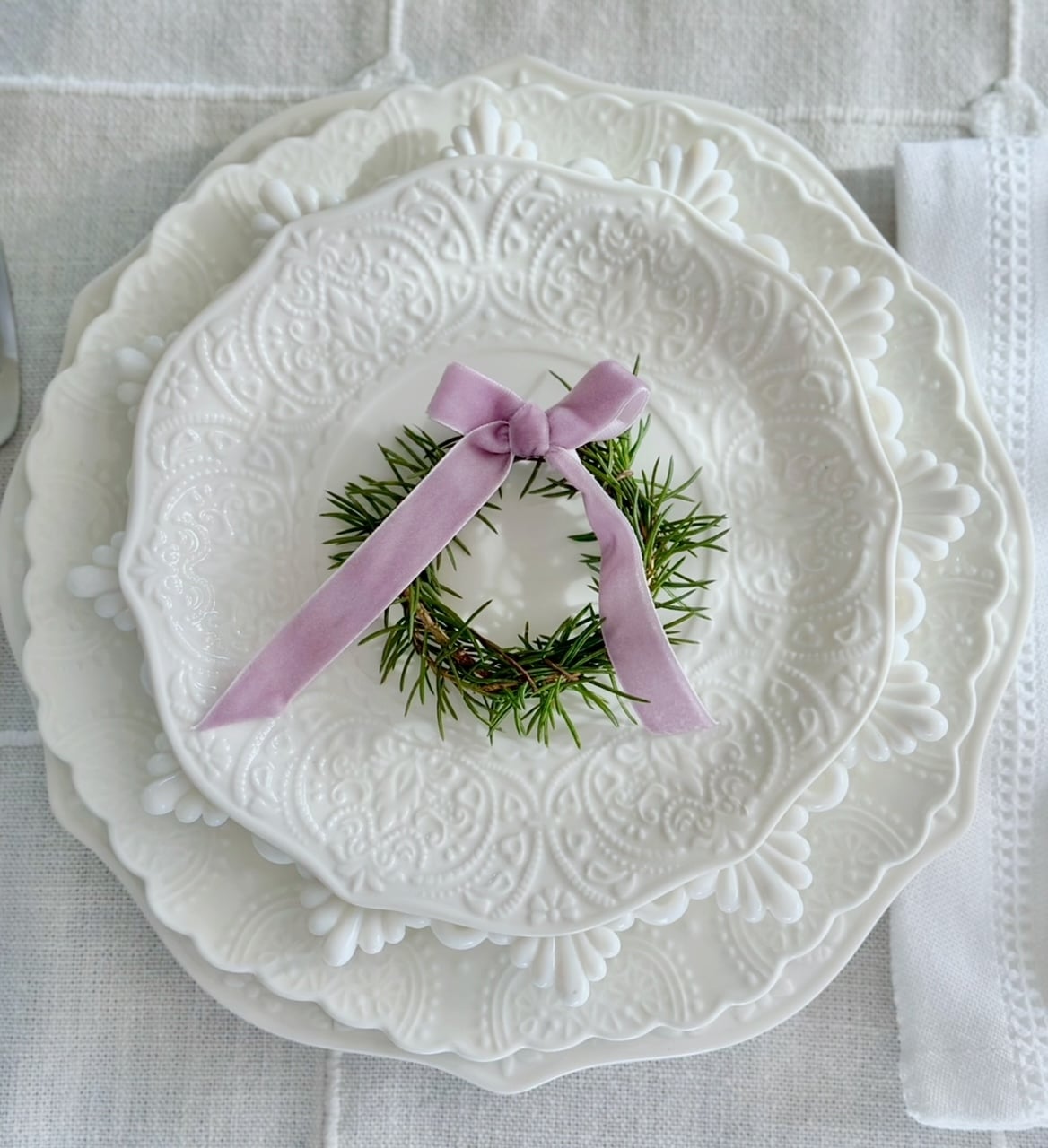 All white placesetting with a rosemary wreath with bow.