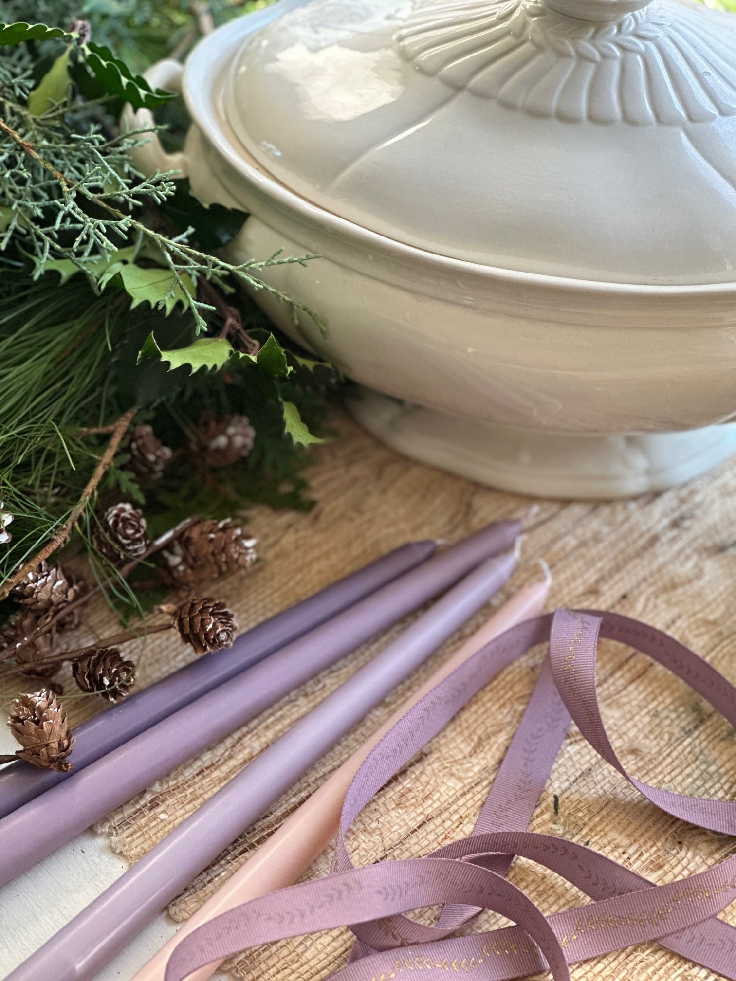 White soup tureen, fresh Christmas greens, ribbon and candles.