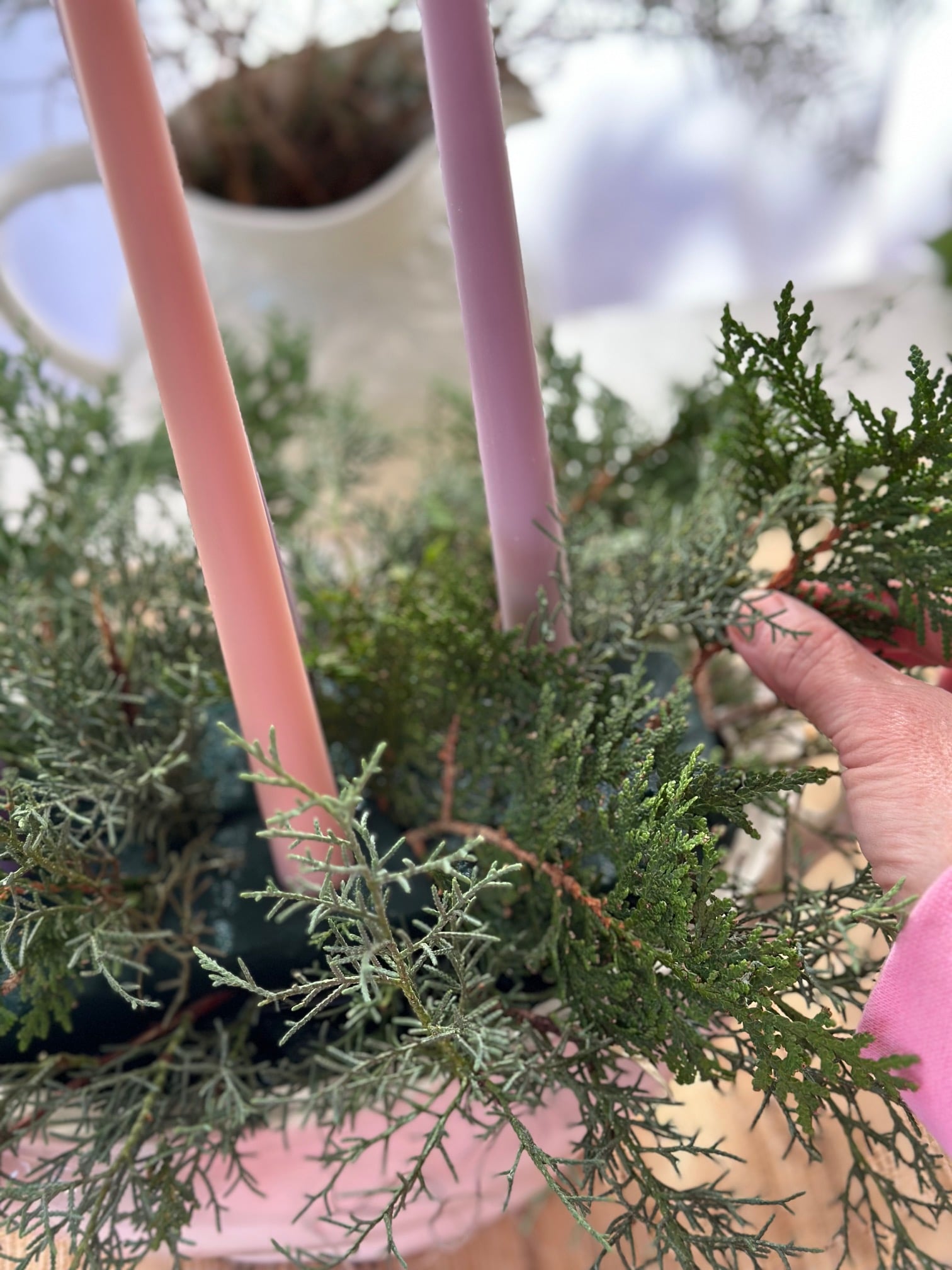 Placing greens and candles into the floral foam.