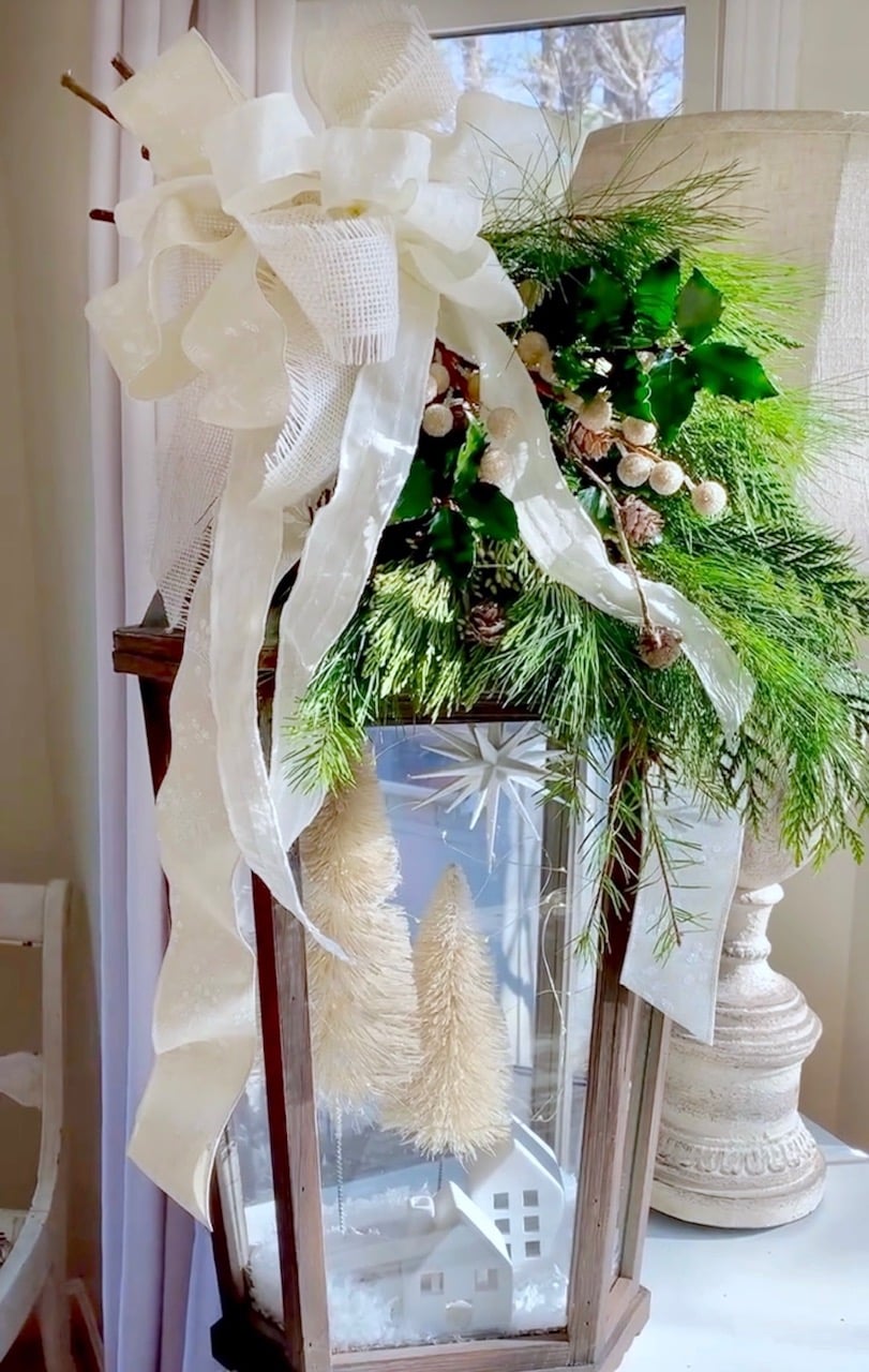 The finished DIY Christmas Lantern with greens and a big bow. 