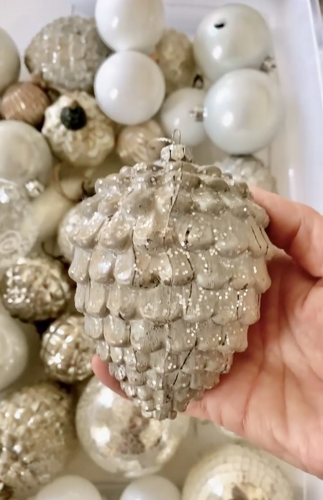 A beige pinecone shaped ornament with sparkles.