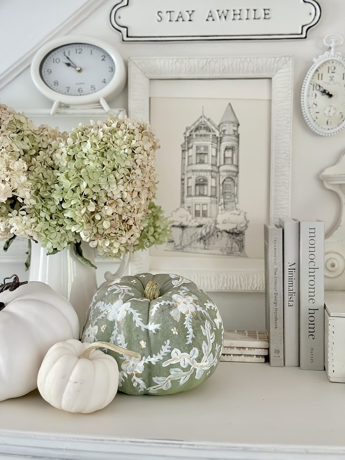 A large green pumpkin with white flowers and leaves painted on.