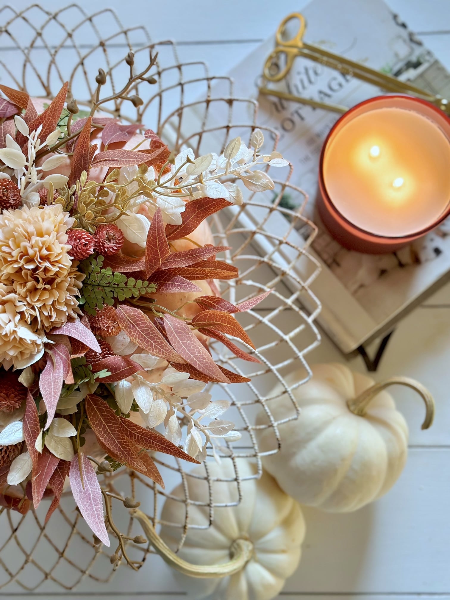 The top of the pumpkin with the faux flowers with pumpkins and a candle.