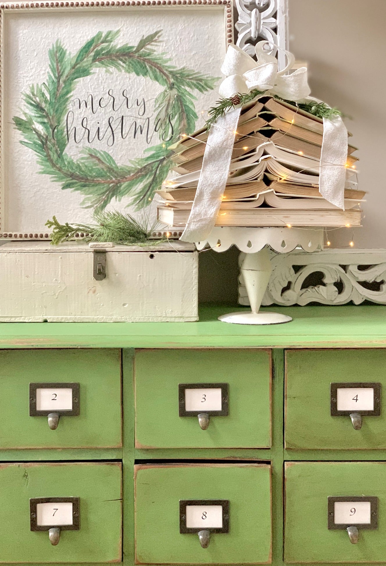 Green card catalog with a book tree on it. A Merry Christmas sign is in the background. 