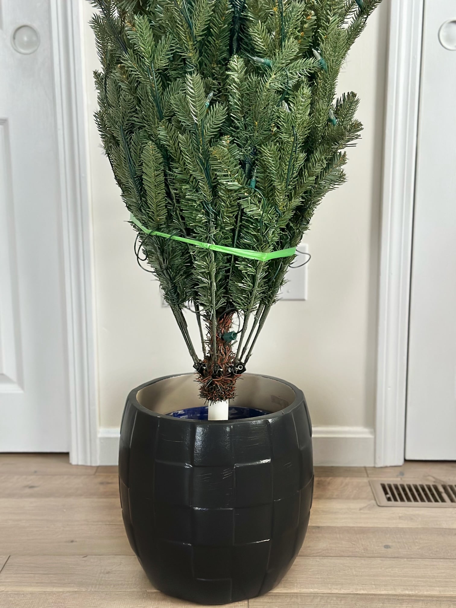 Minimalist artificial Christmas tree planter in a black ceramic pot.