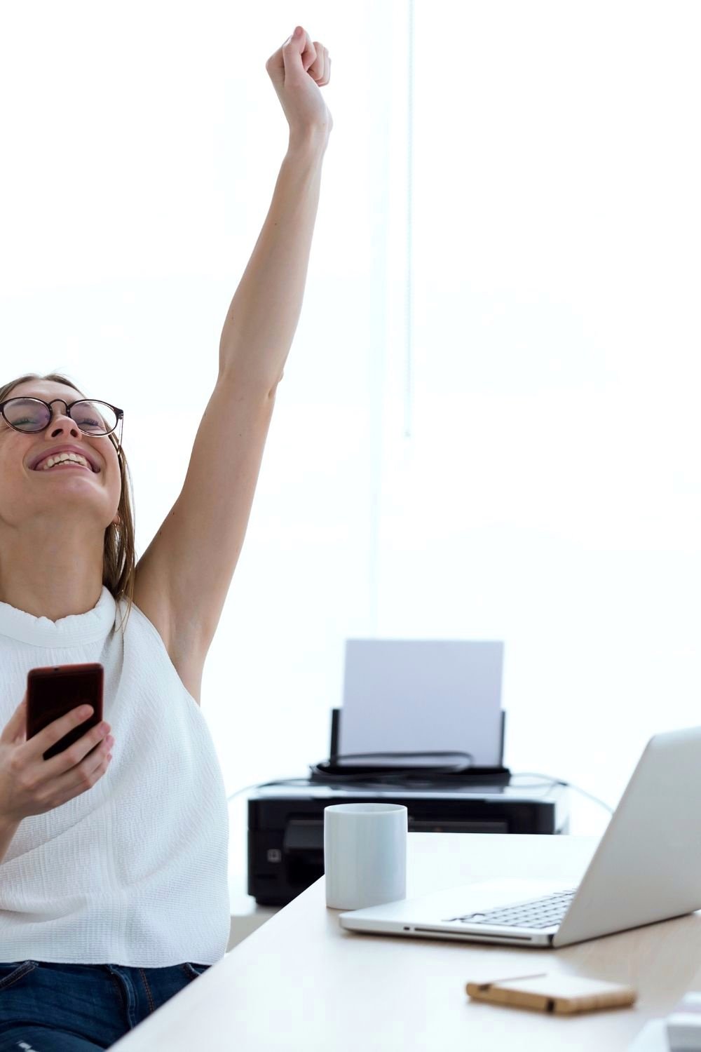 Girl sitting at a computer with hand in the air celebrating a win. 