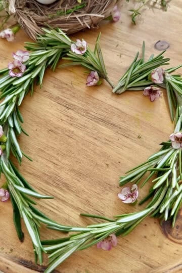 Heart shape wreath of rosemary with small wax flowers.