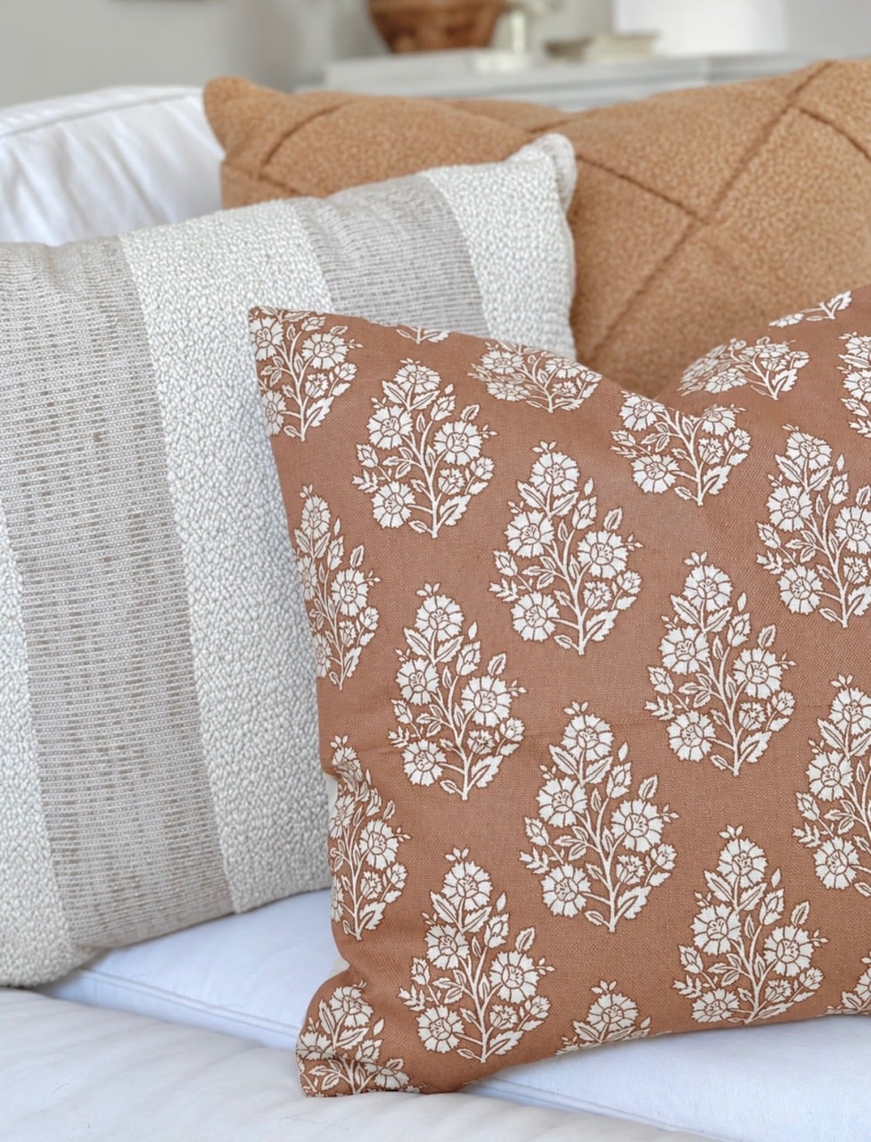 Boucle fabric cross pattern pillow in a terra cotta color, stripe pillow and small flower block pillow in terra cotta.