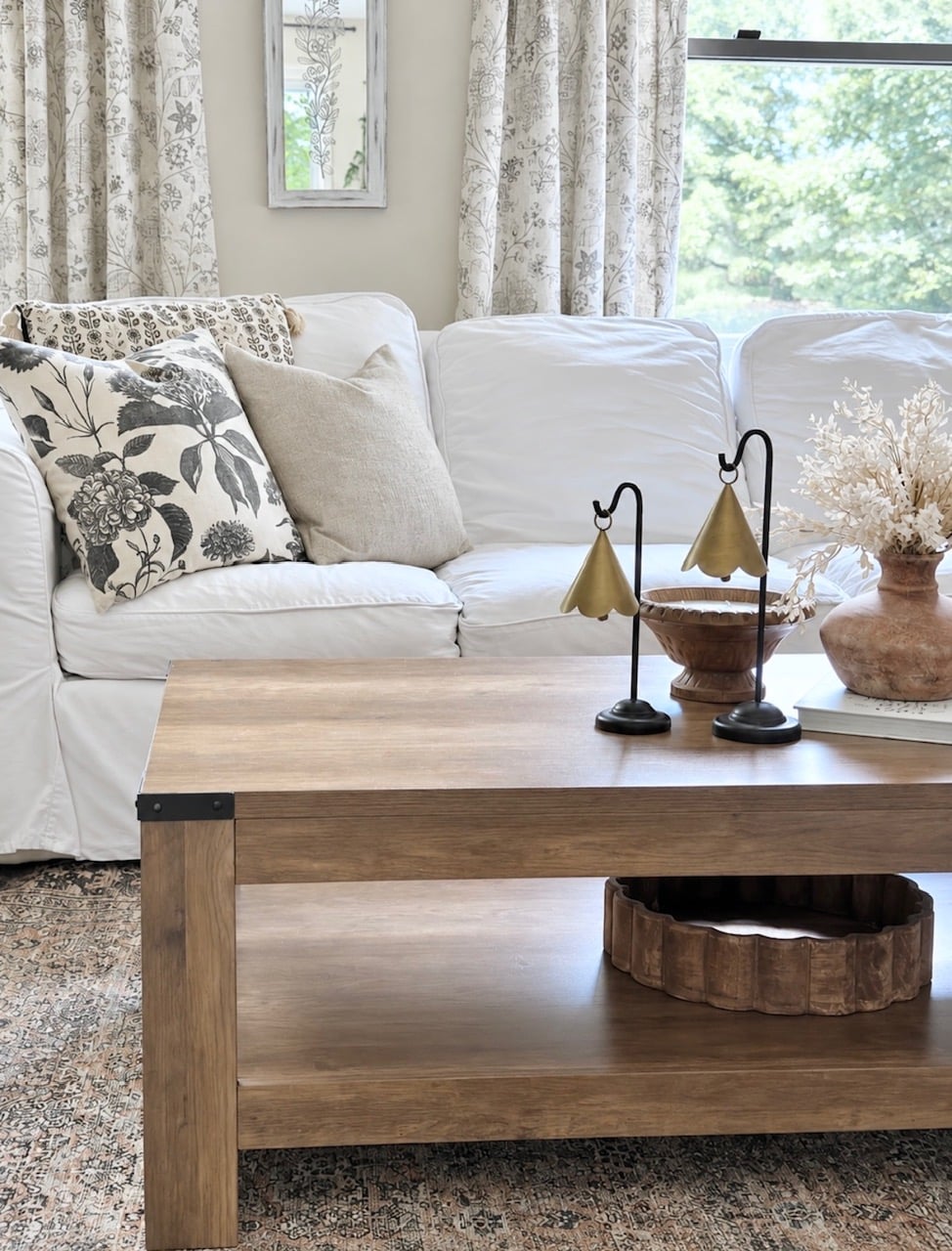My white couch with a cluster of throw pillows. in the foreground is my styled coffee table.