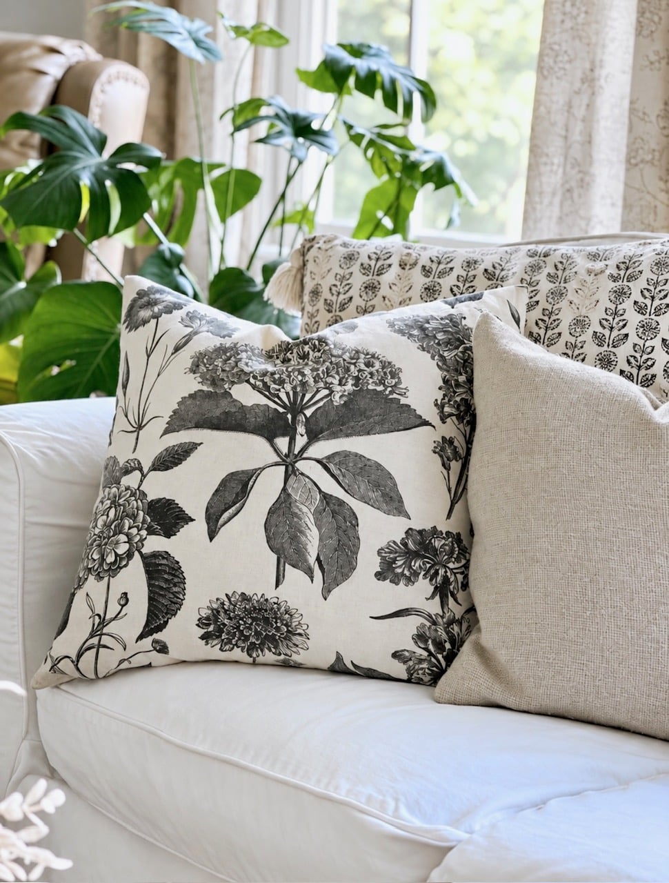 A collection of 3 pillows a large floral, smaller floral and a stripe. All neutral.