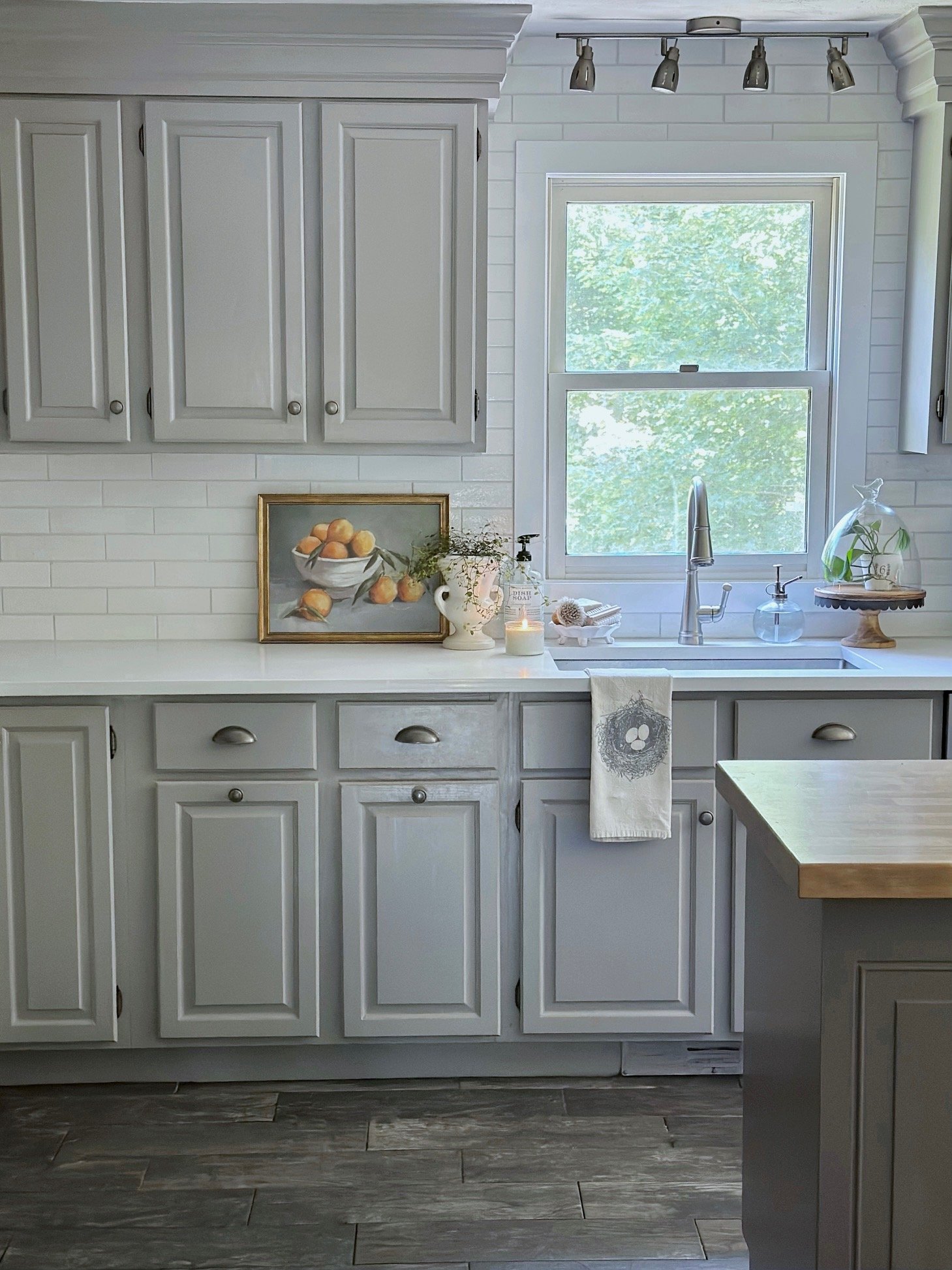 Light gray kitchen cabinets with a white quartz counter and tile backsplash.