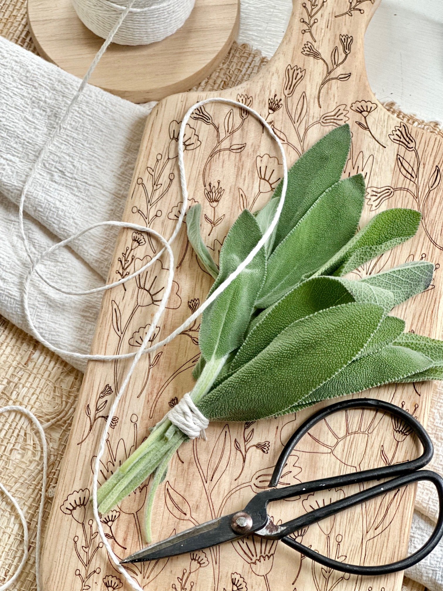 Fresh sage bundle laying on a cutting board with twine. 