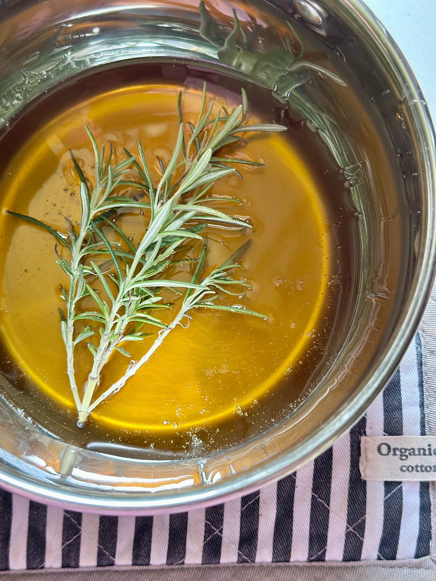 Pot of honey with a sprig of fresh rosemary in it. 