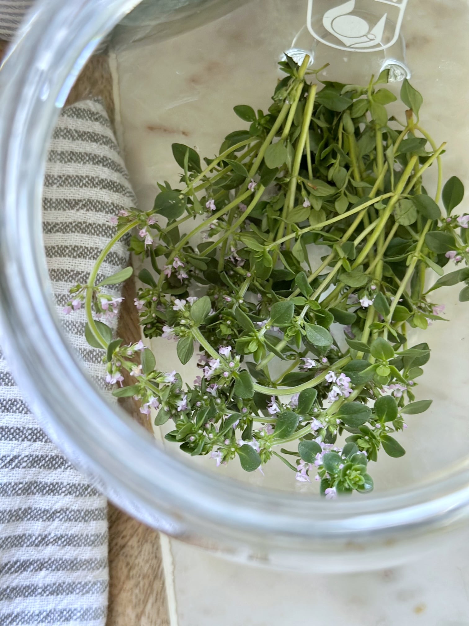 Fresh stems of flowering thyme at the bottom of the jar. 