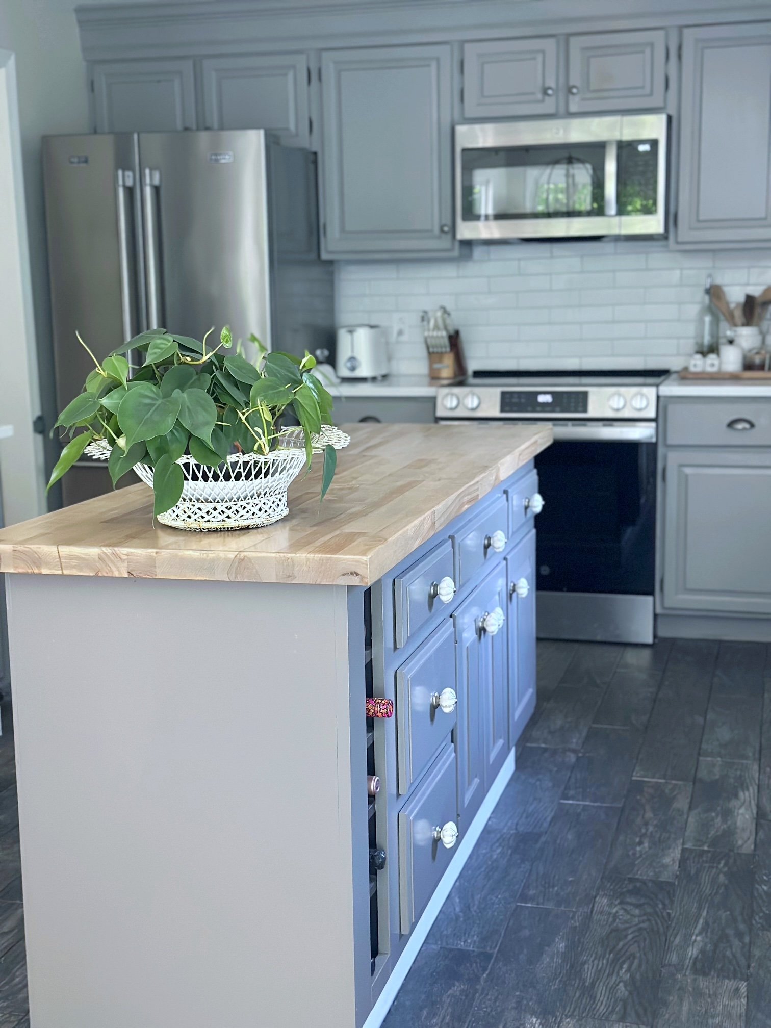 Cheap kitchen island made from recycled bathroom vanities. it is painted dark gray with butcher block counter.