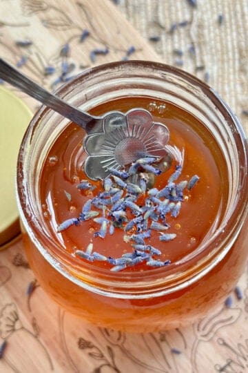 A jar of lavender honey with dried honey in it.