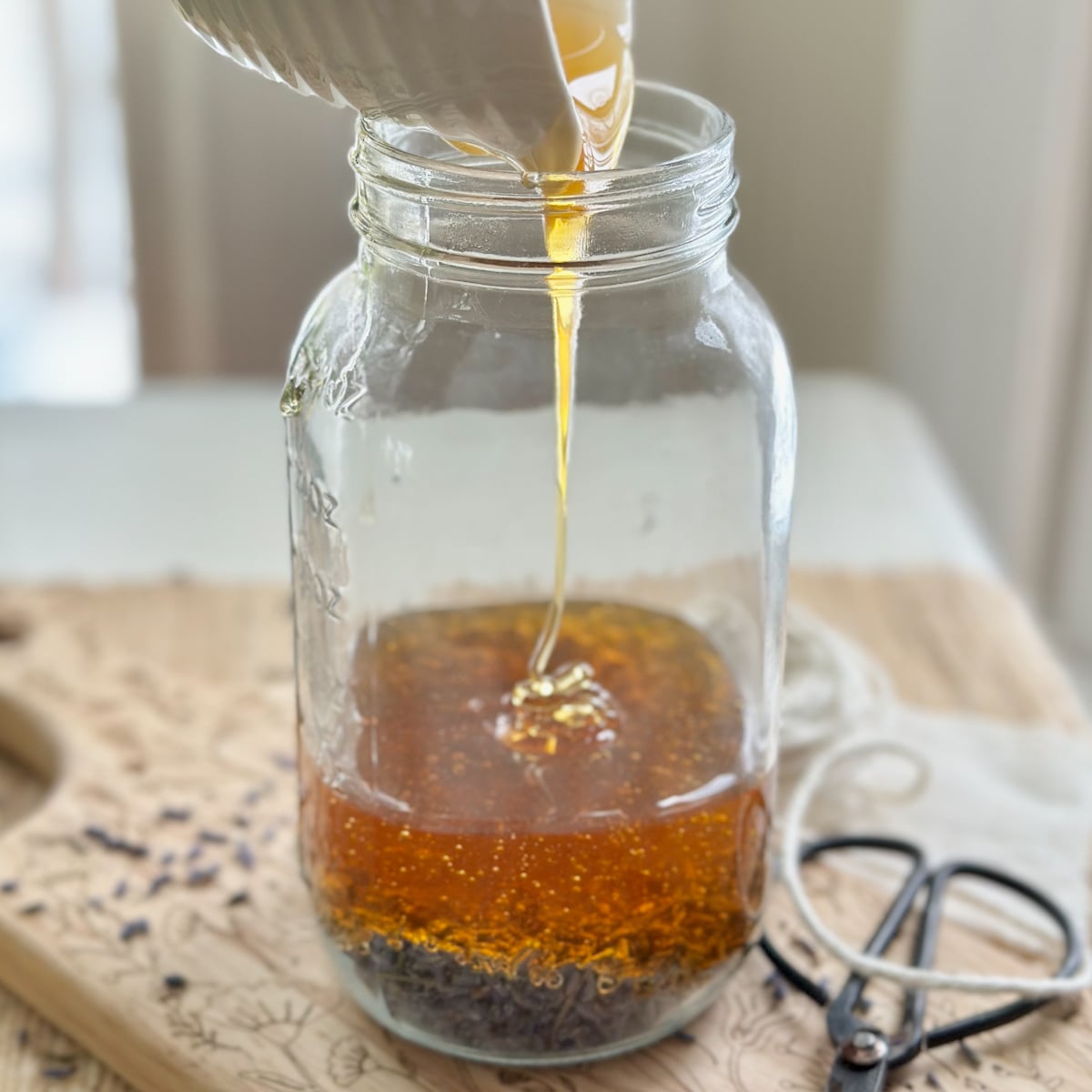pouring honey over lavender in a jar to make infused lavender honey.
