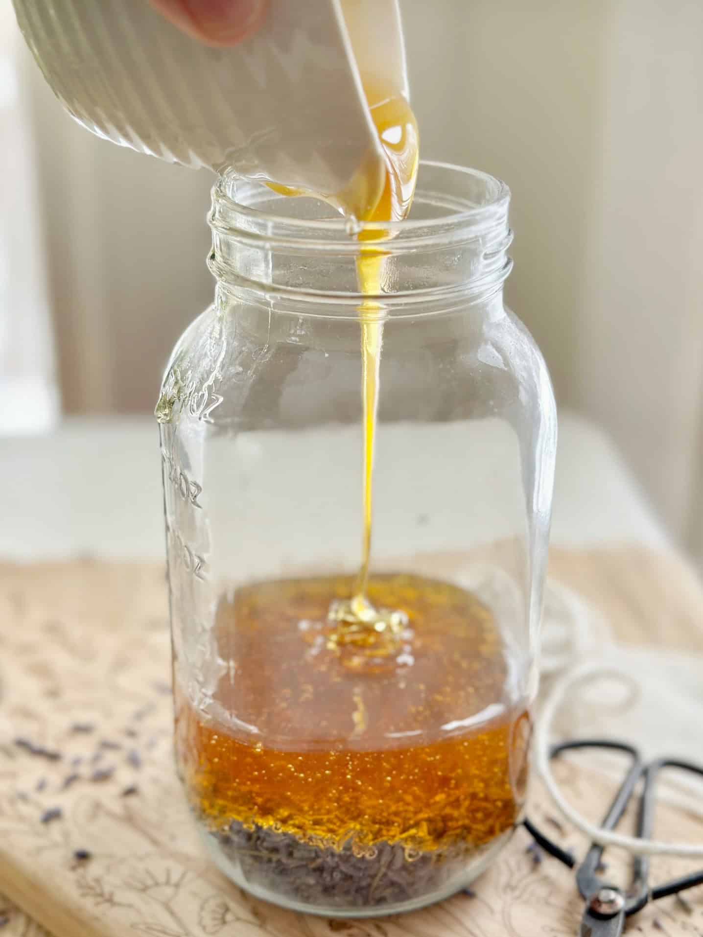 Honey pouring in a jar over lavender. 