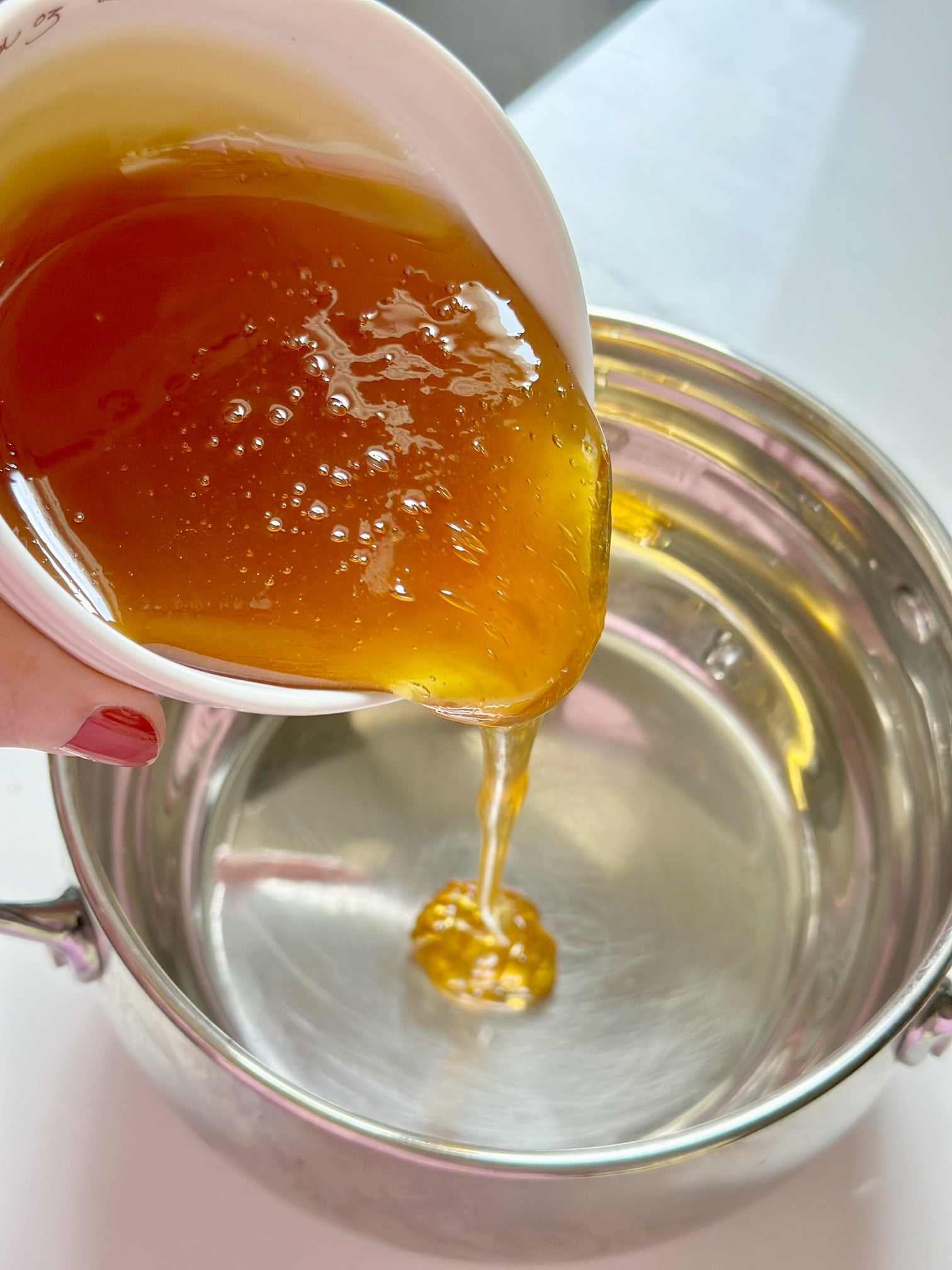 Pouring honey in a pan to heat. 