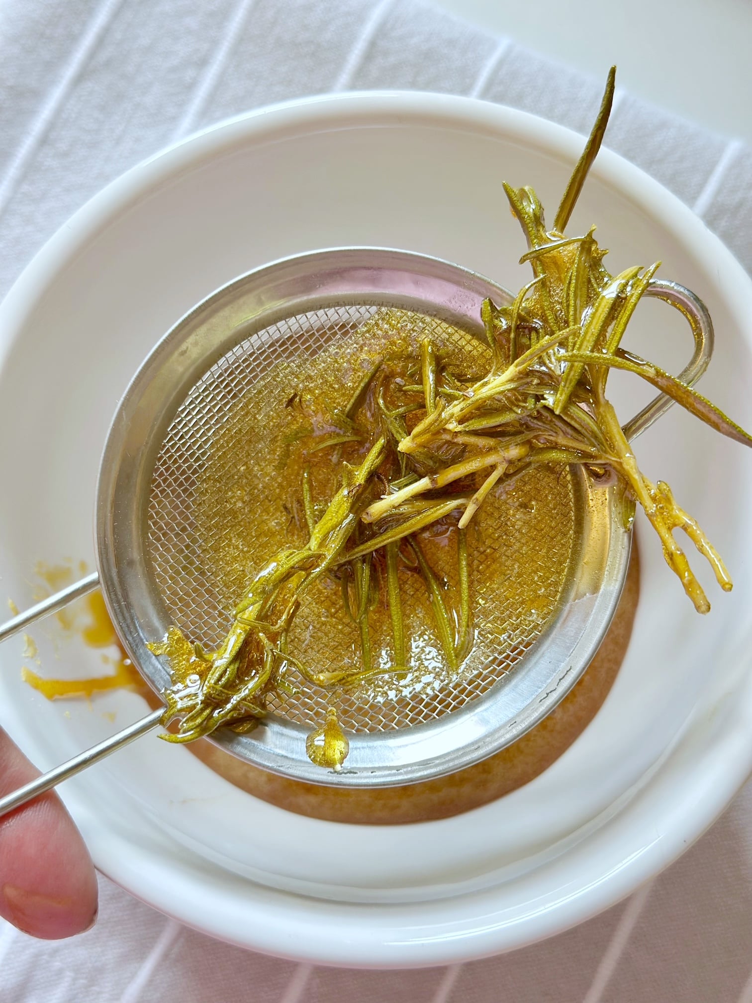 Straining the rosemary from the honey. 